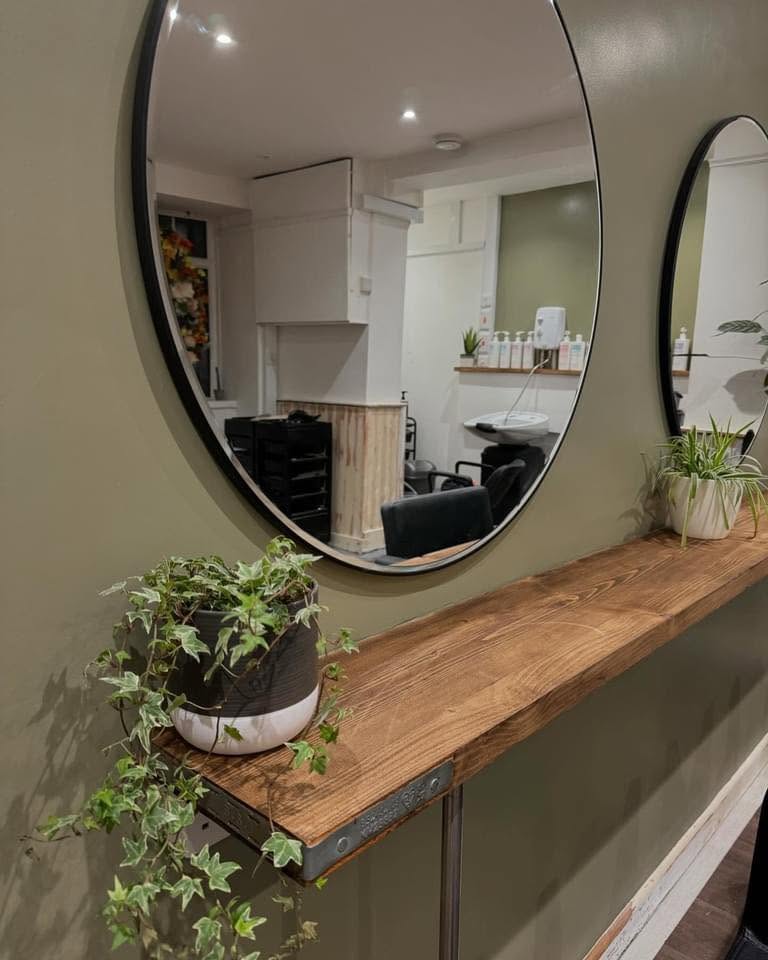 Olive green salon interior with round mirrors and trailing plants